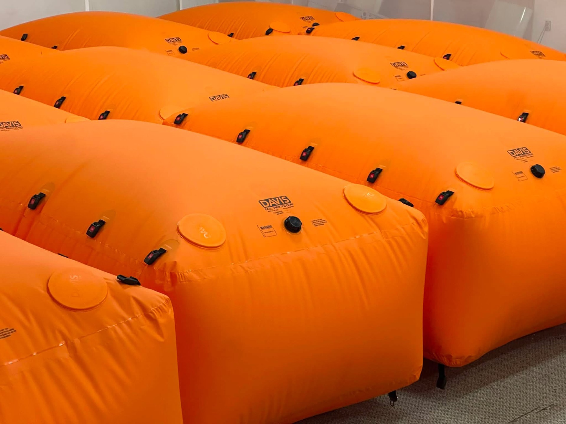 Rows of orange Davis Fall Protection bags showing connection buckles, inflation caps, and round pressure relief covers