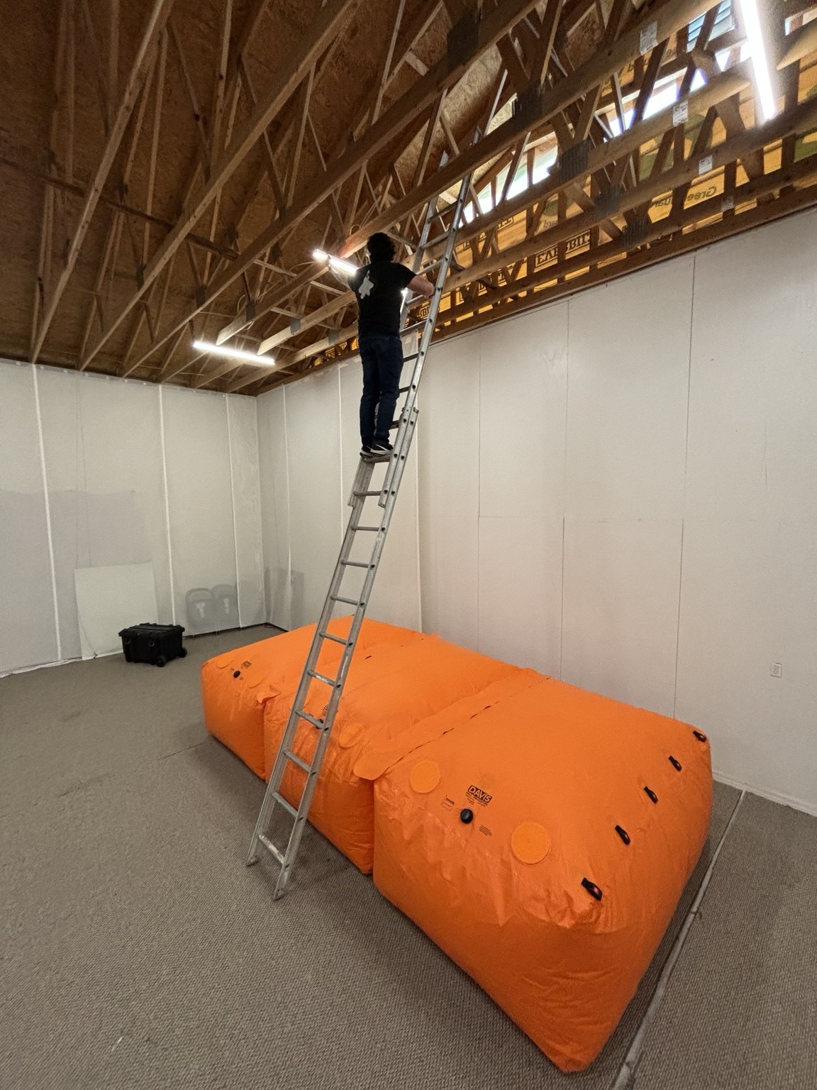 Orange fall protection bags below a ladder in a warehouse